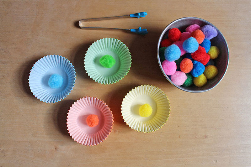 Verschiedene farbige Wattebäuschen in Schalen